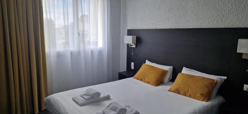 a hotel room with a bed with towels on it at Cit'Hôtel Le Quai 9 , ex Le Challans in Challans