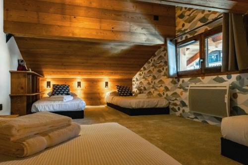 een slaapkamer met 2 bedden in een kamer met houten wanden bij CHALET TEKA LES GETS - Appartement Chery in Les Gets