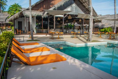 a pool at a resort with chairs and tables at Vanila Hotel & Spa in Ambaro