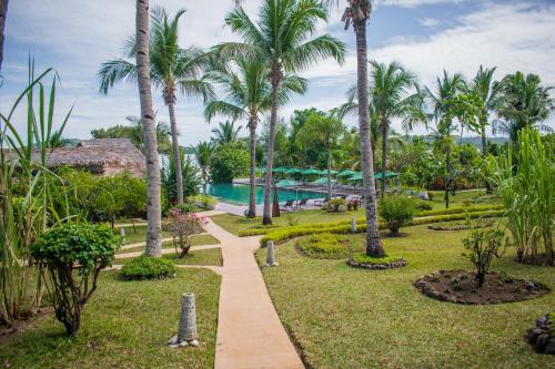 a path through a park with palm trees and a pool at Vanila Hotel & Spa in Ambaro
