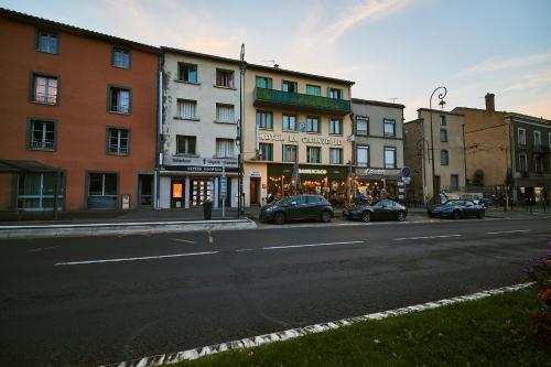 a city street with cars parked in front of buildings at La Caravelle in Riom