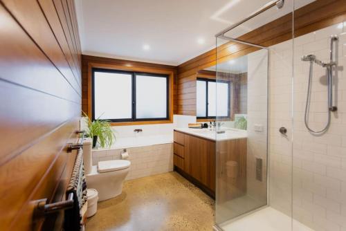 a bathroom with a shower and a toilet and a sink at Mid Century on Eastview in Torquay