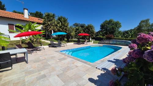- une piscine avec des tables, des chaises et des parasols dans l'établissement Villa Goxoki avec piscine Saint Jean Pied de Port, à Saint-Jean-Pied-de-Port