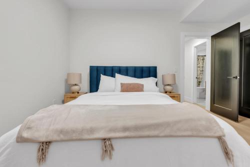 Un dormitorio con una gran cama blanca con cabecero azul. en Cozy 1BR Pullout Couch Discovery Ridge, en Calgary