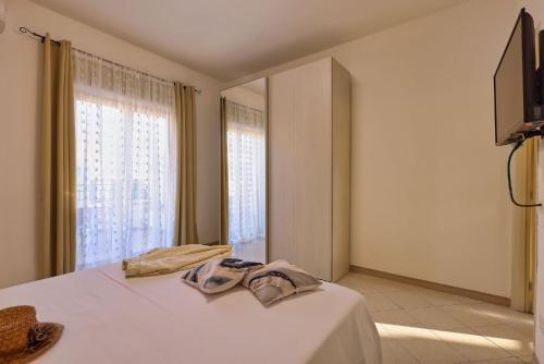 a bedroom with a white bed with a television on the wall at Bedda Sicily in Riposto