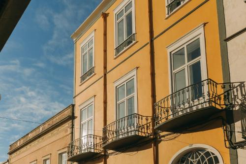 a yellow building with balconies on the side of it at Casa do Contador - Suites & Pool in Ponta Delgada