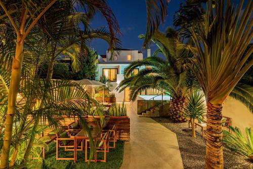 a patio with chairs and palm trees in front of a house at Casa do Contador - Suites & Pool in Ponta Delgada