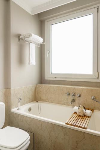a bathroom with a tub and a toilet and a window at Casa Lucia Member of Melia Collection in Buenos Aires