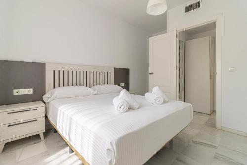 a bedroom with a large white bed with towels on it at Allo Apartments Ático Jaramago Parking Centro 1 Hab in Jerez de la Frontera