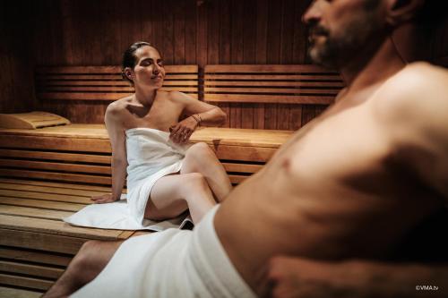 a man and a woman sitting in a sauna at Vivea Hotel Umhausen im Ötztal in Umhausen