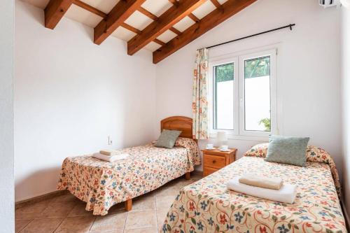 a bedroom with two beds and a window at Villa Airosa by Villa Plus in Cala'n Porter