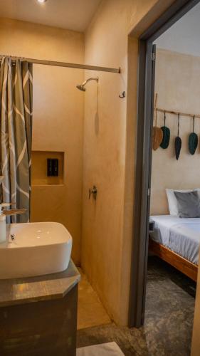 a bathroom with a sink and a shower and a bed at Charming colonial-style room in the heart of Valladolid in Valladolid