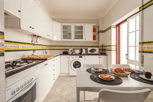 a kitchen with white cabinets and a table with food on it at Topside Luz Guesthouse in Luz