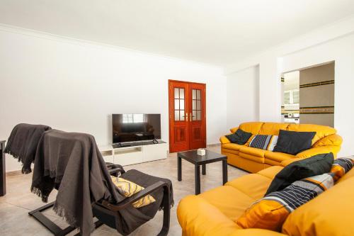 a living room with two couches and a tv at Topside Luz Guesthouse in Luz