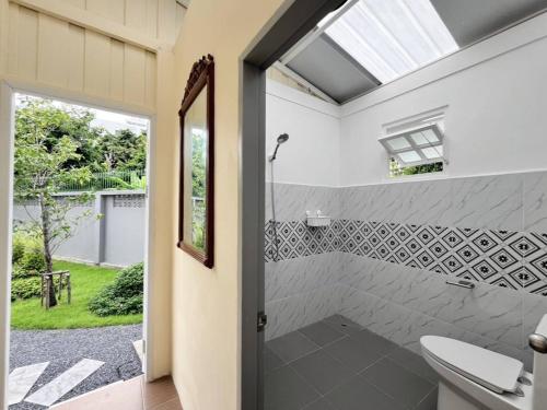 a bathroom with a shower with a toilet and a window at White & Green Guesthouse in Bangkok Yai