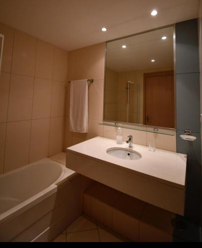 ein Badezimmer mit Waschbecken, Badewanne und Spiegel in der Unterkunft Studio with pool in Santa Maria