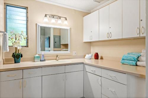 a white bathroom with a sink and a mirror at Sandpiper 120A in Princeville
