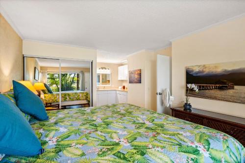 a bedroom with a large bed with blue pillows at Sandpiper 120A in Princeville