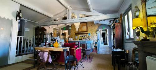 a room with a table and chairs and a bar at Hôtel Bien-Être Aux Cyprès de Marquay in Marquay