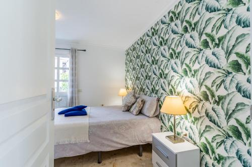 une chambre avec un lit avec un papier peint tropical dans l'établissement Encantador piso en centro de Puerto de la Cruz con gran terraza, à Puerto de la Cruz