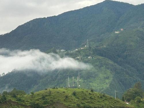 a view of a mountain with clouds on it at Fauji Di Hatti in Kandāghāt