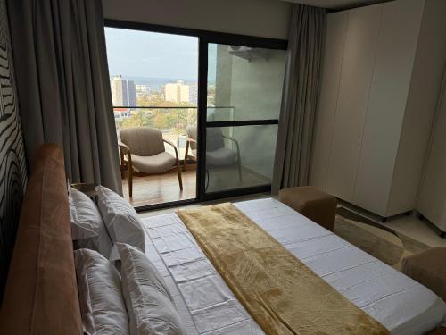 Un dormitorio con una cama y una ventana grande. en Piscine à débordement, Rooftop, Vue Mer & Babyfoot, en Dakar