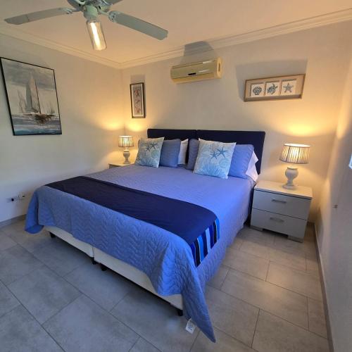 a bedroom with a bed with blue sheets and two lamps at Villa in Sunset Crest, Holetown in Saint James