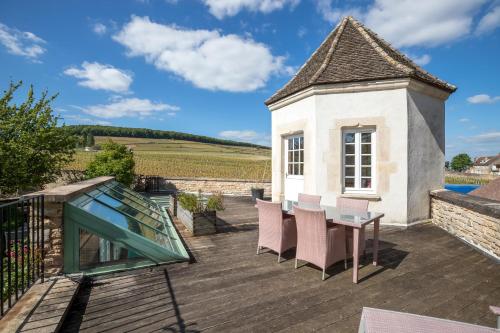 a patio with a glass table and chairs on a roof at Villa Louise in Aloxe-Corton