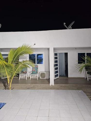 a white house with chairs and a palm tree at Bleu Marin Résidence hôtelière in Hila-Kondji