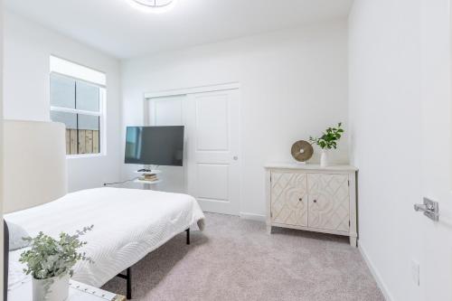 a white bedroom with a bed and a television at Spacious 4BR-3BA Cozy and Modern in Elk Grove in Elk Grove