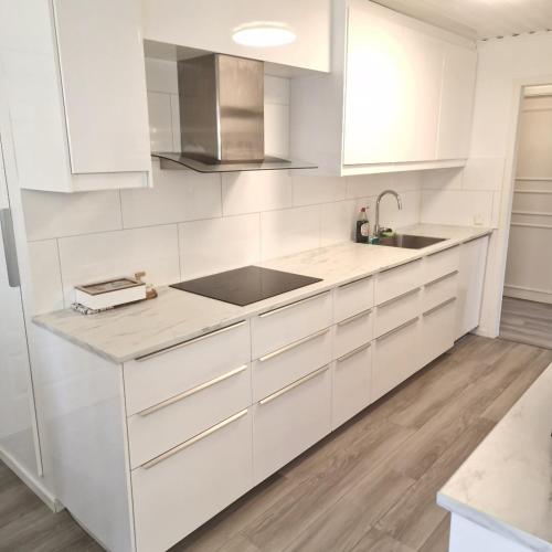 a white kitchen with white cabinets and a sink at Luxury Villa in Mjölby