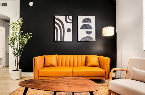 an orange couch in a living room with a table at Boulevard Stays Chic 1BR Near Stadium Pool Access Gym & Free Parking in Glendale