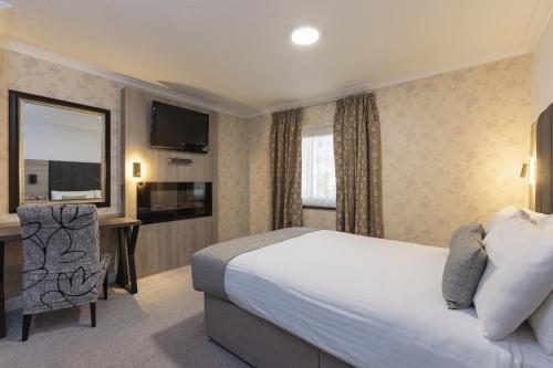 a hotel room with a bed and a desk and a television at Durrant House Hotel in Bideford