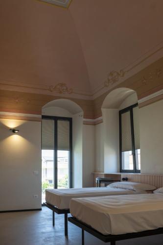 two beds in a large room with two windows at Casale della Vittoria in Taranto