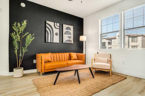an orange couch and a chair in a living room at Boulevard Stays Luxe 1BR by Stadium Pool Parking Gym 07 in Glendale