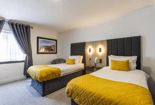 two beds in a hotel room with yellow pillows at Durrant House Hotel in Bideford