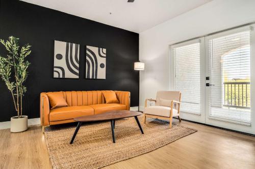 a living room with an orange couch and a table at Boulevard Stays Luxe 2BR by the Stadium Pool Parking Gym 05 in Glendale