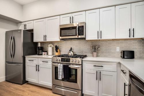 a kitchen with white cabinets and stainless steel appliances at Boulevard Stays Luxe 2BR by the Stadium Pool Parking Gym 05 in Glendale