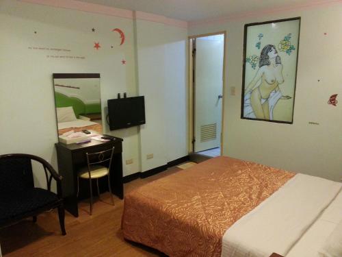a bedroom with a bed and a desk and a mirror at Rido Hotel in Taichung