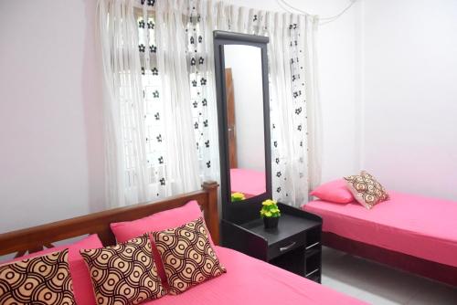 a bedroom with two pink beds and a mirror at Dulina Holiday Homes in Anuradhapura