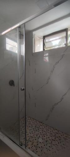 a shower with a glass door in a bathroom at CulturaHumana Guesthouse in Panama City