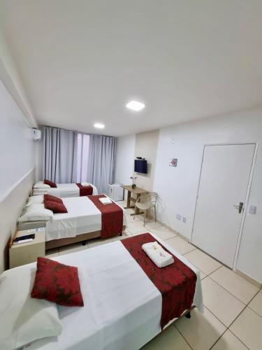 a hotel room with three beds and a table at Max Hotel in Brasilia