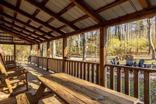 a wooden porch with a wooden bench on a deck at Serene Retreat Hot Tub, Fire Pit, Arcade Fun in Townsend
