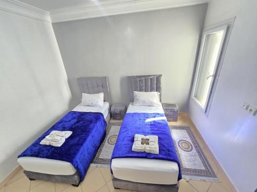 - 2 lits dans une petite chambre avec des draps bleus dans l'établissement Appartement freedom, à Agadir