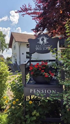 a black sign in front of a house with flowers at Pension Miss Sophie in Kyritz