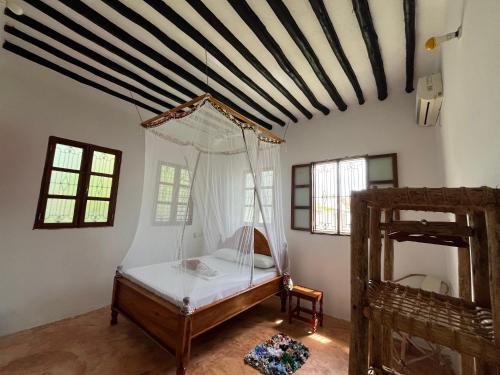 a bedroom with a canopy bed in a room at Naira House in Jambiani