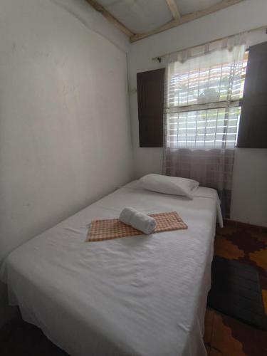 a bedroom with a white bed with a window at Makarius in Santa Fe de Antioquia