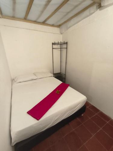 a white bed with a red napkin on it at Makarius in Santa Fe de Antioquia