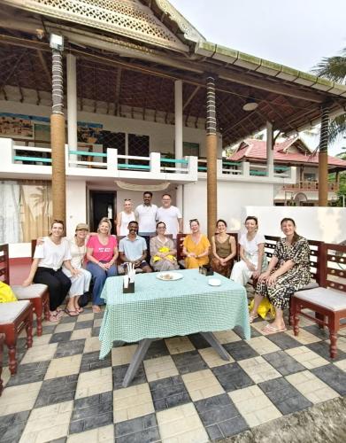 a group of people sitting around a table on a patio at Marari Praise Beachfront Homestay in Mararikulam