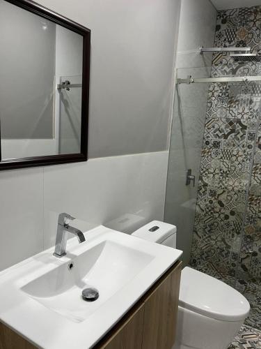 a bathroom with a sink and a toilet and a mirror at MH Apartments Ica 3 in Ica
